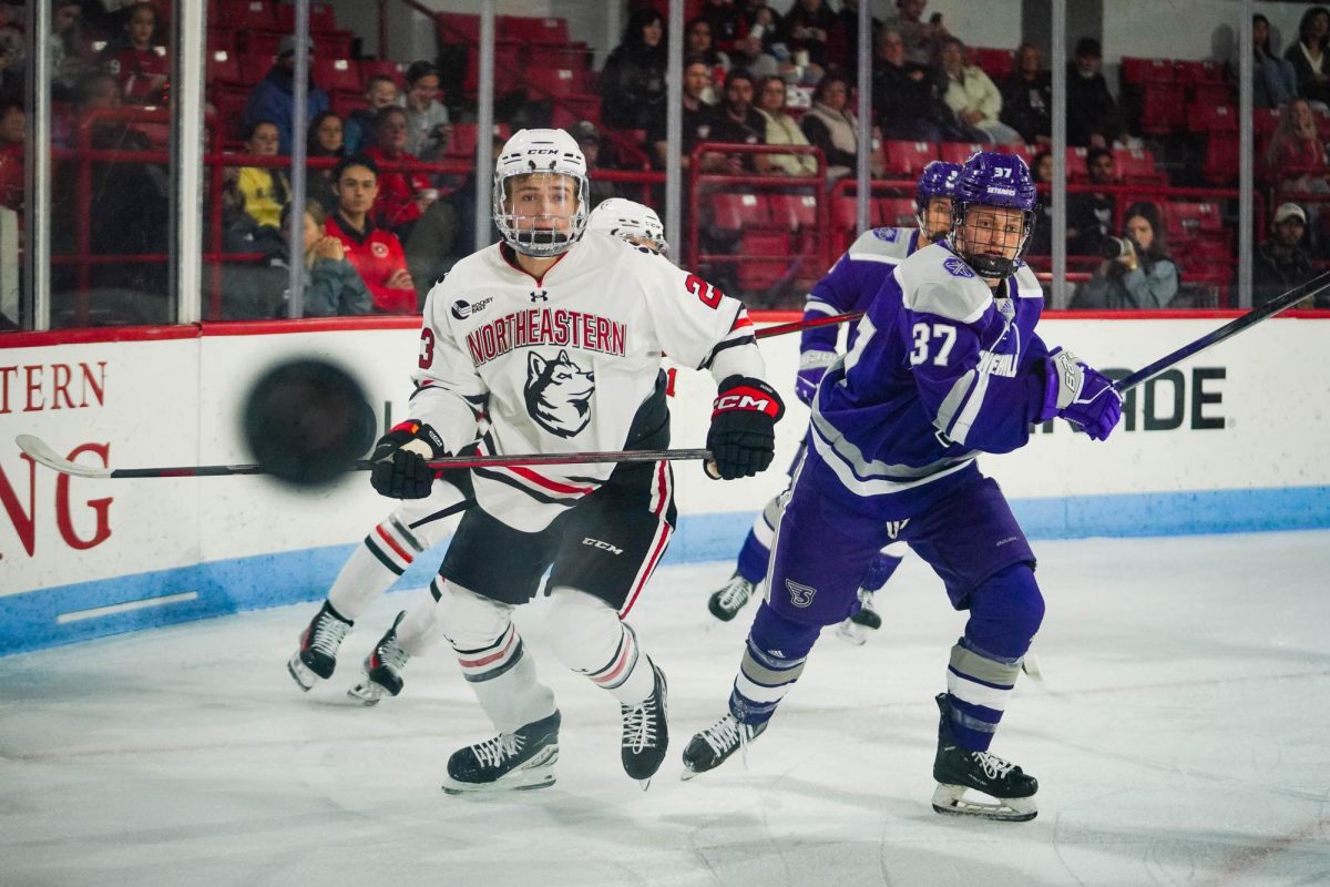 Freshman forward Ben Poitras eyes the puck as it flies across the ice in Northeastern's matchup against Stonehill Oct. 12. The Huskies totaled 35 shots compared to the Skyhawks' 18.